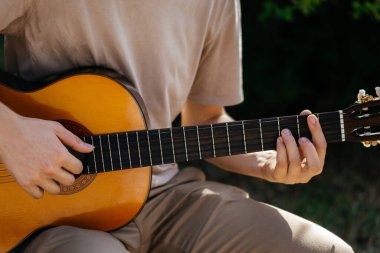 Genç adamlar dışarıda akustik gitar çalıyorlar. Yüksek kalite fotoğraf