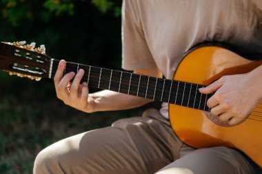 Genç adamlar dışarıda akustik gitar çalıyorlar. Yüksek kalite fotoğraf