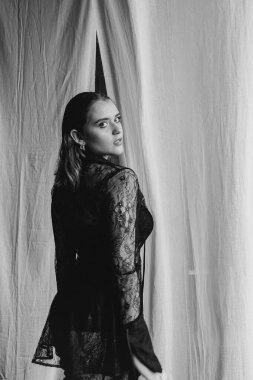 Saf siyah dantelli, kendine güvenen kadın beyaz perdeler arasında duruyor, somut güç, zarafet ve modern gotik moda. Yüksek kalite fotoğraf