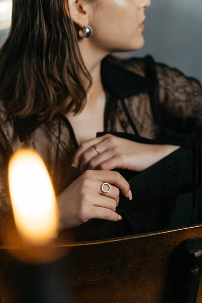 Таинственная женщина в черных кружевах позирует со свечой в дымящейся готической обстановке рядом со старинным пианино. Высокое качество фото