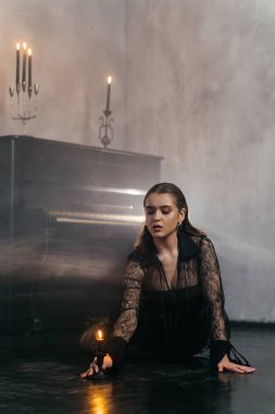 Siyah dantelli gizemli kadın dumanlı, gotik bir ortamda klasik bir piyanonun yanında poz veriyor. Yüksek kalite fotoğraf