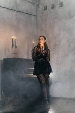 Siyah dantelli gizemli kadın dumanlı, gotik bir ortamda klasik bir piyanonun yanında poz veriyor. Yüksek kalite fotoğraf