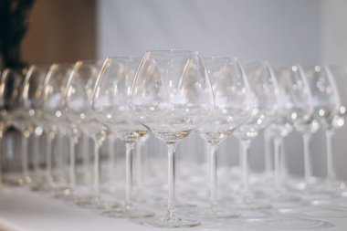 Bir sıra zarif boş şarap kadehi yumuşak odak noktasında parlıyor, zarif ve şenlikli bir atmosfer yaratıyor. Yüksek kalite fotoğraf