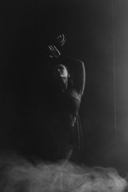 Gizemli bir kadın gölgeler ve dumanlarla çevrili parlak bir pencereye karşı siluet içinde duruyor. Yüksek kalite fotoğraf