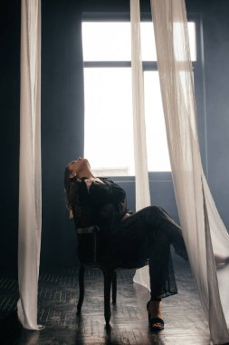 Saf siyah dantelli, kendine güvenen kadın beyaz perdeler arasında duruyor, somut güç, zarafet ve modern gotik moda. Yüksek kalite fotoğraf