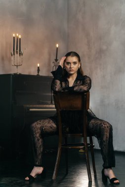 Siyah dantelli gizemli kadın dumanlı, gotik bir ortamda klasik bir piyanonun yanında poz veriyor. Yüksek kalite fotoğraf