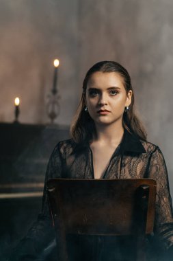 Siyah dantelli gizemli kadın dumanlı, gotik bir ortamda klasik bir piyanonun yanında poz veriyor. Yüksek kalite fotoğraf
