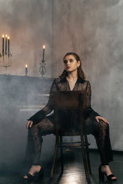 Siyah dantelli gizemli kadın dumanlı, gotik bir ortamda klasik bir piyanonun yanında poz veriyor. Yüksek kalite fotoğraf