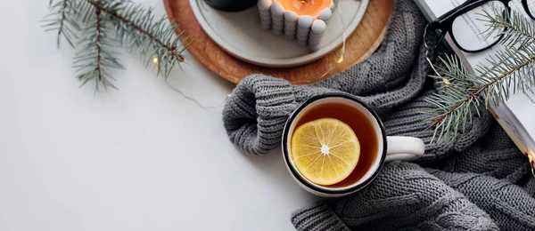 Sabah limon çayı, açık kitap, sıcak kazak, mumlar ve köknar ağacı. Refah, sabah ritüelleri, yararlı alışkanlık konsepti. Üst görünüm, boşluğu kopyala. Tasarım için pankart.