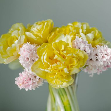 Güzel pembe şakayıklı laleler buketi ve vazodaki beyaz masadaki cam vazoda pembe sümbül. Doğum günü için hediyeler, 8 Mart, Anneler Günü, Sevgililer Günü, Kadınlar Günü, Paskalya.