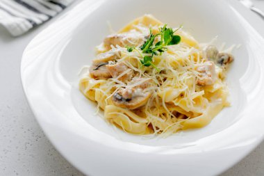 Tavuklu makarna, şampiyon mantarı, hafif arkaplanda parmesan..