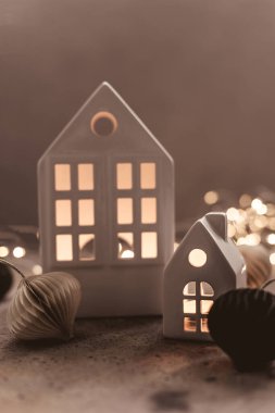 Beyaz seramik evi ve arka planda kağıt balonu olan bir Noel arkaplanı. Noel arka planında çelenk ışıkları bokeh.