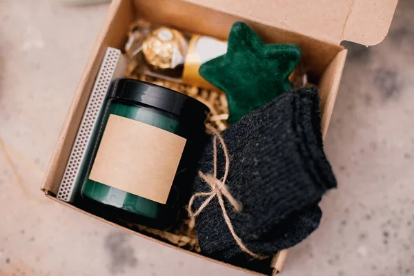 圣诞礼盒 蜡烛插在黑罐子里 巧克力糖果 舒适的灰色袜子和节日装饰 寒假个人用品箱 图库图片