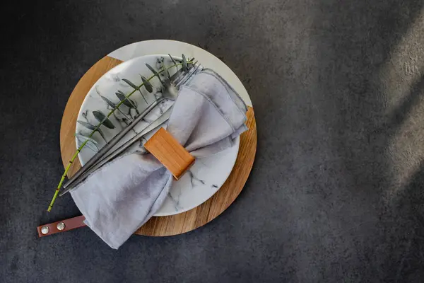 复活节餐桌设置的概念 深色背景桌上的盘子 餐具和桉树枝条 带有复制空间的顶部视图 免版税图库照片