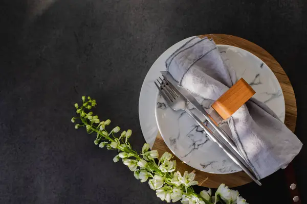 复活节餐桌设置的概念 深色背景桌上的盘子 餐具和春花 免版税图库照片