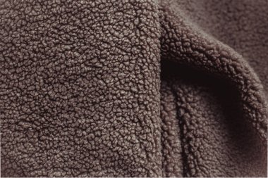 Mocha Mousse yün ceketi kumaş ve elastik kelepçelerini sergiliyor, sıcaklığı ve rahatlığı ifade ederken karmaşık kumaş detaylarını vurguluyor. Yıl Rengi 2025.