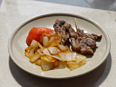 Tabakta soğanlı ve domatesli ızgara kuzu eti.