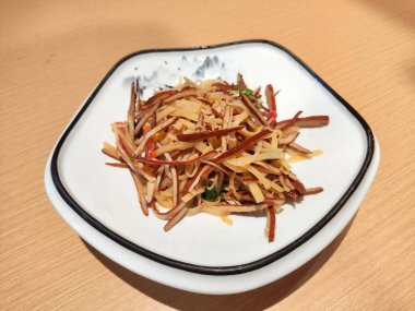 Beyaz tabakta tofu ipeğiyle çırpılmış patates.