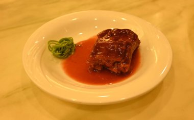 Taze pişmiş domuz bifteği ve yemek için beyaz tabakta yeşil erişte.