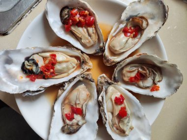 Taze haşlanmış istiridye ve kırmızı biberli beyaz tabak yemek için.