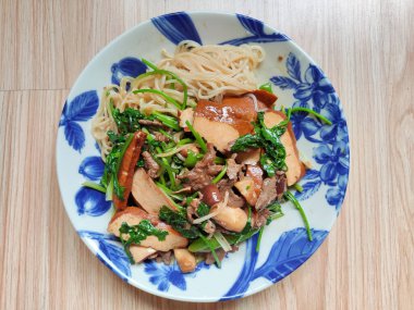 Yeşil sebzelerle çırpılmış sığır eti ve mavi tabakta eriştenin üzerinde soya peyniri.