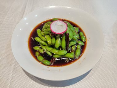 Taze tuzlu ve soslu yeşil fasulye ve beyaz kasede bir dilim lale.