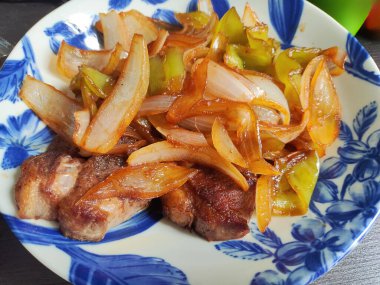 Taze soğan. Mavi tabakta domuz bifteği var.