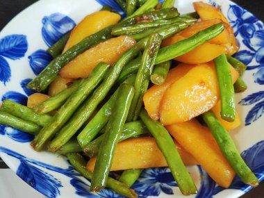 Mavi tabakta uzun fasulyeli taze dilimlenmiş patates.