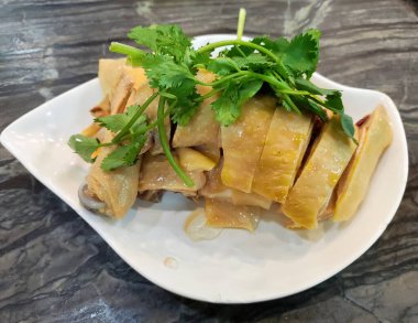 Beyaz tabakta yeşil kişniş ile kaplı taze tavuk.