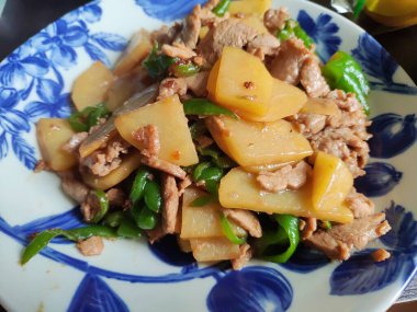 Patatesle çırpılmış et ve yeşil biberli mavi tabak yemek için.