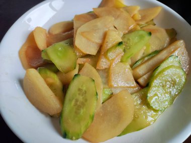 Salatalık, yemek için beyaz tabakta patates ile çırpılmış.