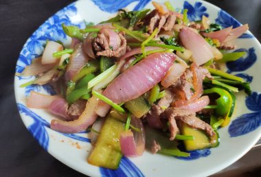 Mavi tabakta soğanlı ve yeşil sebzeli sığır eti.