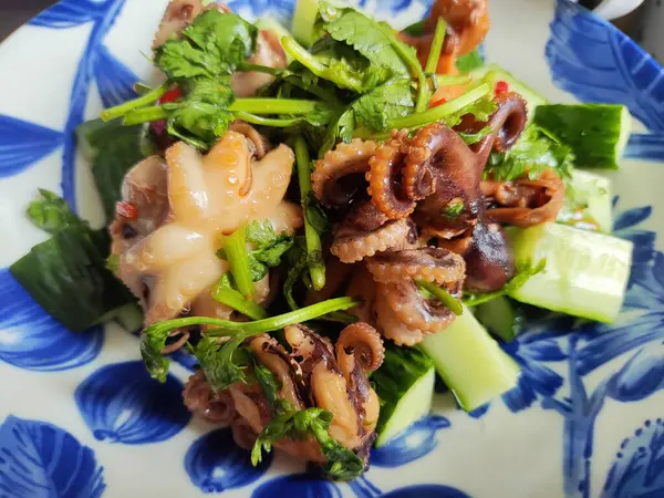 Mavi tabakta yeşil sebzelerle pişirilmiş taze mürekkep balığı.