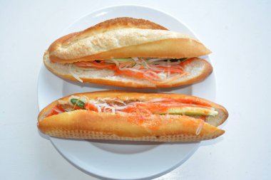 Beyaz tabakta sebzeli iki ekmek hazır.