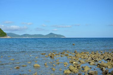 Mavi gökyüzünün altında güneşli bir günde dağ ve deniz manzarası