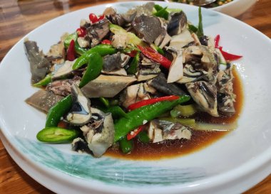 Beyaz tabakta yeşil ve kırmızı biberli Sichuan biberi tavuğu.