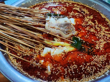 Kırmızı baharatlı yağlı çorbada taze Sichuan bobo tavuğu yemek için.
