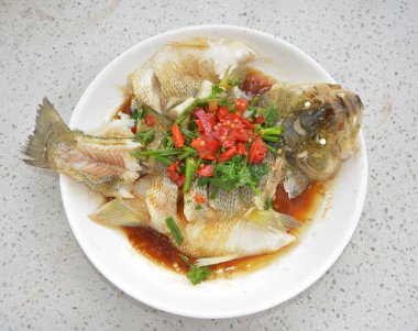 Braised fish with green vegetables and red peppers on the plate for eating clipart