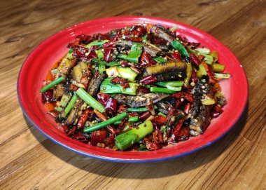 Kırmızı tabakta yeşil sarımsaklı ve kırmızı biberli yılan balığı eti.