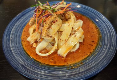 Kırmızı tabakta sebzeli soğuk erişte yemek için mavi tabakta.