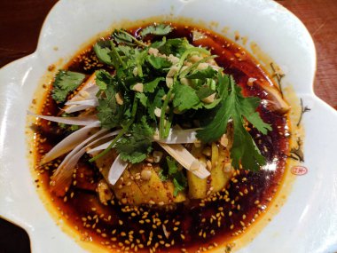 Haşlanmış tavukta yeşil sebze ve kırmızı yağlı biber sosu.