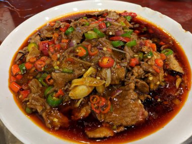 Beyaz tabakta baharatlı çorbada yeşil ve kırmızı biberli taze haşlanmış biftek.