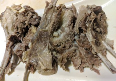 Beyaz tabakta parlak ışıkta kaynamış koyun eti.