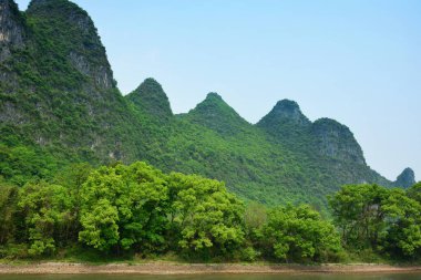 Çin 'in Guilin kıyısındaki nehir kıyısında bulunan dağ ve ağaçlar.