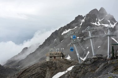 Sisli bir günde kar dağında mavi teleferik.