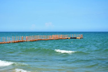 Güneşli bir öğleden sonra Hainan 'da deniz suyunun üzerindeki plastik turuncu iskele.