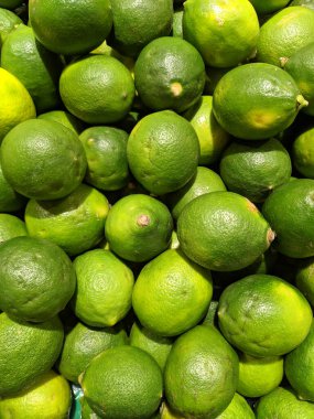 Yeşil limonlar parlak ışığın altında süpermarkette görünüyor.