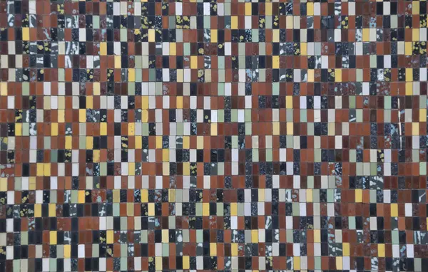 Farklı renklerde seramik dikdörtgenlerle kaplı bir duvarın yüzey dokusu