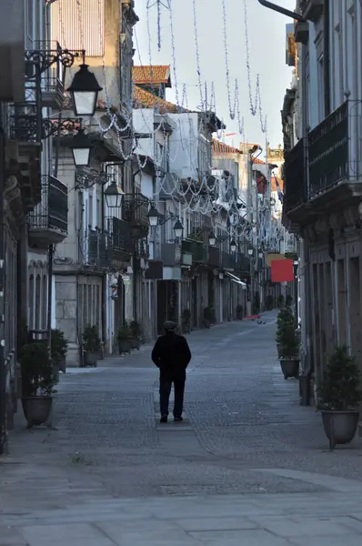 Portekiz 'in kuzeyindeki Viana do Castelo şehrindeki eski bir sokakta sabah yürüyen yaşlı bir adam.