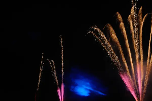 Pembe, altın ve mavi ışıklarda havai fişekler, gece gökyüzünde, kutlama ve şenlik günü